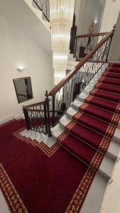 a stairway with a red carpet and a staircase with a chandelier at Vila Băncii 1888 by SunGarden in Băile Herculane