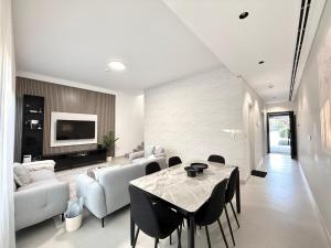 a living room with a table and chairs and a couch at Sahab - Masar 2BR Townhouse in Sharjah