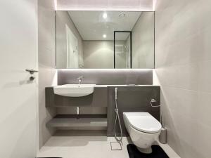 a bathroom with a sink and a toilet and a mirror at Sahab - Masar 2BR Townhouse in Sharjah