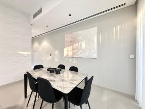 a dining room with a marble table and chairs at Sahab - Masar 2BR Townhouse in Sharjah +49 photos