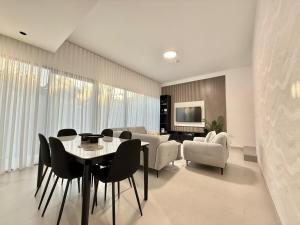 a living room with a table and chairs and a couch at Sahab - Masar 2BR Townhouse in Sharjah