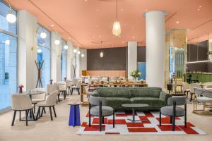 a lobby with a green couch and tables and chairs at Hotel Lycium Debrecen - Handwritten Collection in Debrecen +31 photos