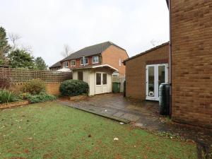 a house with a yard next to a brick building at Orchard Place Semington By N And N Stays, 20 Mins From Bath, Perfect for Contractors and Workers, Pvt Parking for 2 vehicles 