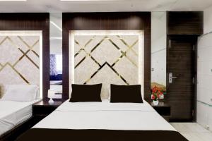 una habitación con una cama grande con sábanas y almohadas blancas en Collection O Chidambaram Stadium Formerly Hotel Admire Suit, en Chennai