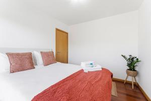 a bedroom with a white bed with a red blanket at GuestReady - Terrace Cozy Stay in Coimbra