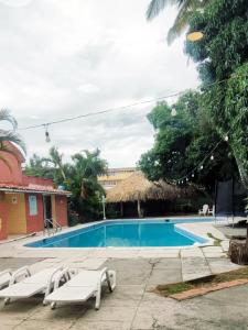 a swimming pool with two white chairs next to a building at Hotel Mediterraneo Plaza in San Salvador