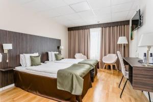 Una habitación de hotel con una cama grande y un escritorio. en Hotell Nova, en Karlstad
