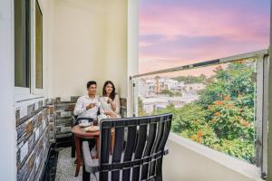 a man and woman sitting on a balcony looking out a window at FabHotel Eminent - Patel Nagar, 0riental University in Bhopal