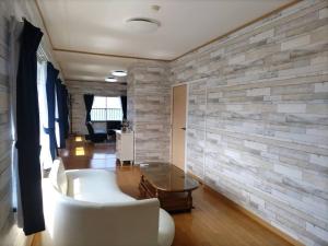 uma sala de estar com um sofá branco e uma parede de pedra em Pension Le Passage - Vacation STAY 53145v em Tottori