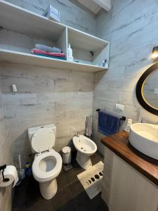 a bathroom with a white toilet and a sink at Casa 109 in Necochea +9 photos