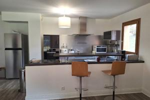 Una cocina con mostrador y dos sillas de bar. en Modern apartment in the heart of Séez, en Séez