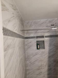 a bathroom with a shower with white marble tiles at Denver Layover B&B in DEN