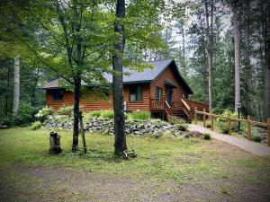 una baita di tronchi nel bosco con una recinzione di Manitowish Mike’s a Manitowish Waters