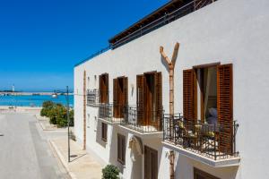 サン・ヴィート・ロ・カーポにあるMira Spiaggiaの白い建物(茶色のシャッター、バルコニー付)