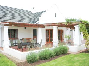 a house with a patio with chairs and a table at Wingrock Guesthouse in George
