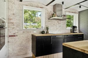 a kitchen with black cabinets and a brick wall at Fjord-Close Cottage With Beautiful View in Hemmet