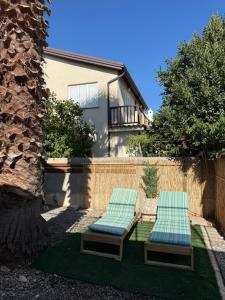 Dos tumbonas verdes en un patio trasero con una casa. en Onyx Beach Villa - Cozy 2BR - Walk to Beach, en Meneou