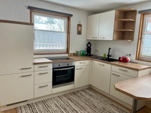 a kitchen with white cabinets and a table and a window at Ferienwohnung Fink in Langenegg