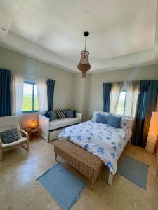 JuanDolio Penthouse 3 bedrooms Beachfront frente a hemingway في Los Corrales: غرفة نوم بسرير واريكة ونوافذ