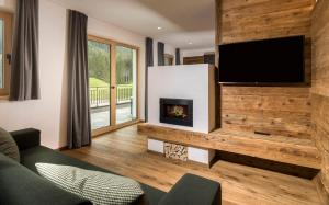 a living room with a fireplace and a flat screen tv at Waidacherhof Apartments in Braies