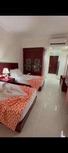 een slaapkamer met twee bedden en een tafel met een lamp bij Oyster Bay Beach Suites in Marsa Alam +64 foto's