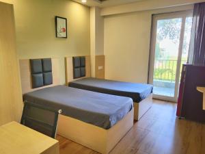 Dos camas en una habitación con ventana. en Kommune Living, en Gurgaon