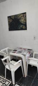 un tavolo con sedie bianche e un dipinto sul muro di Casa em Araçatuba-SP ad Araçatuba
