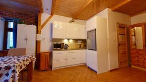 una cucina con mobili bianchi e un tavolo in una stanza di Apartamenty SZUMiWODA a Karpacz