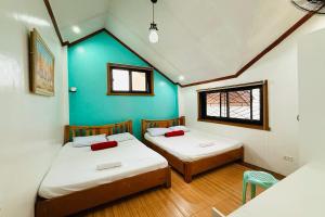 Dos camas en una habitación con una pared azul. en Mountain Transient Lodge, en Baguio