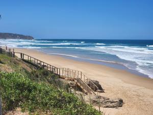 una playa de arena con una escalera que conduce al océano en Lilies and Leopards Holiday Home B & B, en Mossel Bay