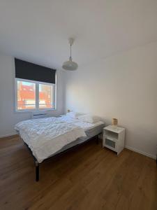 a white bedroom with a bed and a window at Digue & Dream - 4-person apartment in Dunkerque +2 photos