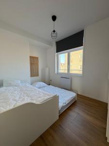 a white bedroom with a bed and a window at Digue & Dream - 4-person apartment in Dunkerque