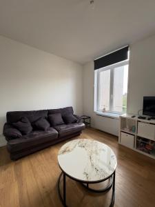 a living room with a couch and a table at Digue & Dream - 4-person apartment in Dunkerque
