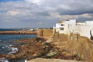 a white building on the rocks next to the ocean at Hotel Estrella del Norte in Larache