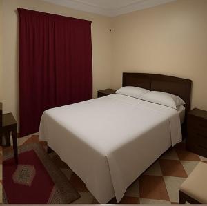 a bedroom with a large white bed and a red curtain at Hotel Estrella del Norte in Larache