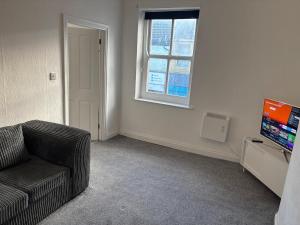 een woonkamer met een bank en een televisie bij Zinoc Seaside Apartment in Murton