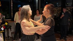 Sumaq Hostel Backpackers في بوينس آيرس: امرأتان تقفان بجانب بعضهما البعض على حلبة الرقص