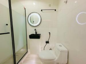 a white bathroom with a toilet and a mirror at LinQues & Bethel Residences in Ibadan +24 photos