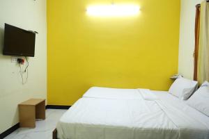 TallākulamLaxmi Palaze的卧室配有白色的床和黄色的墙壁