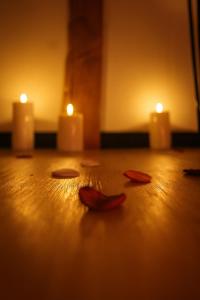 Dos velas encendidas y algunas hojas sobre un piso de madera. en Rendez-vous Secret, en Lunas 24 fotos más