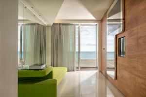 a living room with a green couch and a view of the ocean at i-Suite Hotel in Rimini