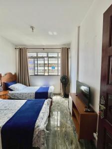 a hotel room with two beds and a television at Quarto Privativo na AvBeira mar - Apto familiar in Fortaleza