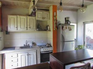 a kitchen with white cabinets and a refrigerator and a sink at La Maruja de Acantilados in Mar del Plata