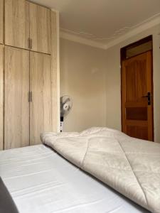 ein Schlafzimmer mit einem weißen Bett und einem Schrank in der Unterkunft P&P homes in Kampala
