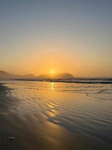 a sunset on a beach with the ocean at Relax on the Beach in Guarujá