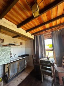 a kitchen and dining room with a table and a window at Cabaña Fran in Punta Del Diablo