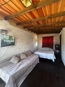 a bedroom with two beds and a tv on a wall at Cabaña Fran in Punta Del Diablo