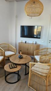 Zimmer mit Stühlen, einem Tisch und einem TV in der Unterkunft Aether Mykonos 3BR Villa with Serene Port & Town Views in Tourlos