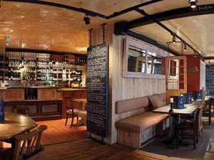 um restaurante com mesas e cadeiras e um bar em The Cross Keys em Saffron Walden