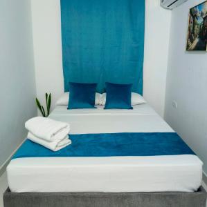 a bed with blue and white sheets and blue pillows at Hospedaje Torices Cartagena in Cartagena de Indias +22 photos